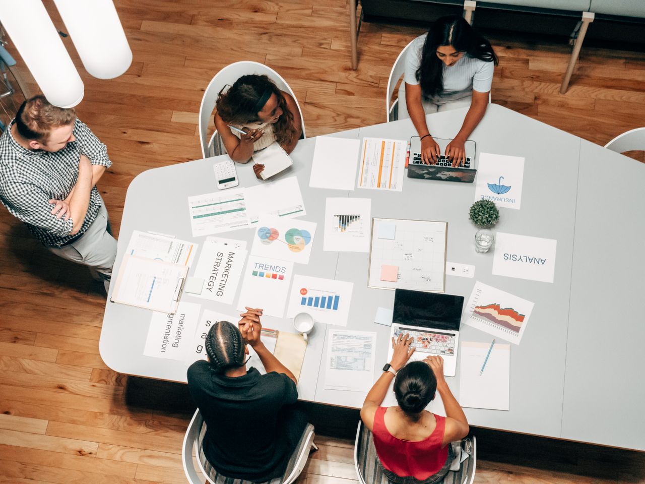Un groupe varié travaillant sur des stratégies marketing avec des graphiques et des ordinateurs portables dans un cadre de bureau.